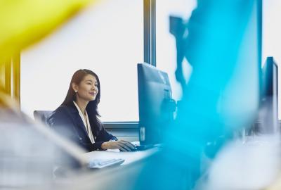 Woman working on her desktop computer. China. Primary color: blue.