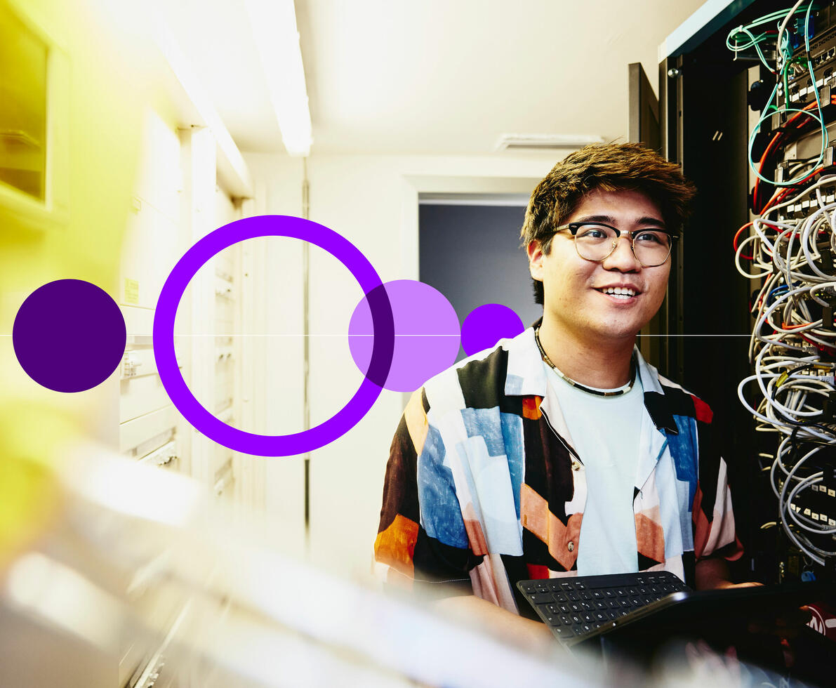 Smiling male holding an tablet standing in a servers room.