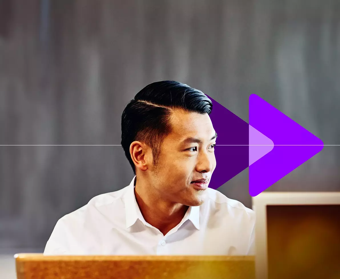 male employee looking away while sitting in front of a desktop computer 