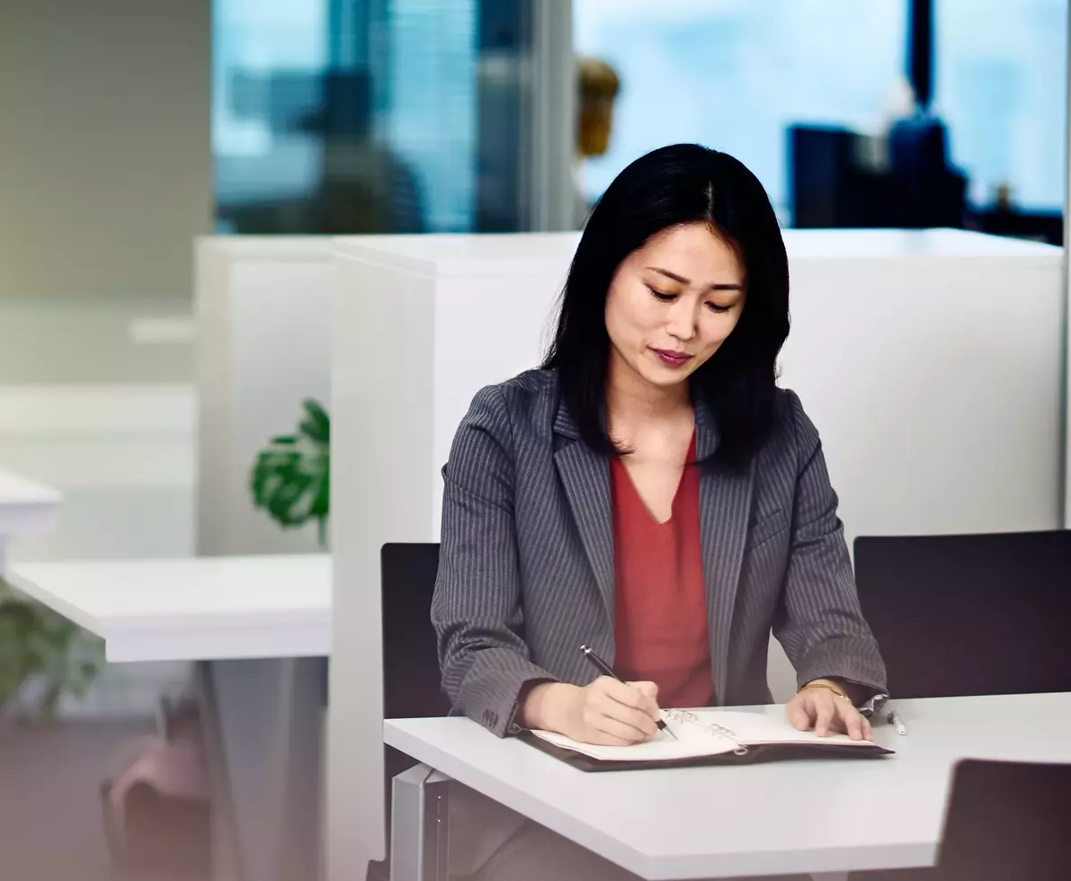 smiling woman writing while seated 