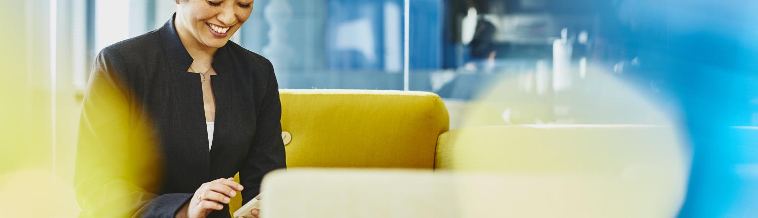Woman looking at her cell phone smiling. Japan. Primary color: yellow.