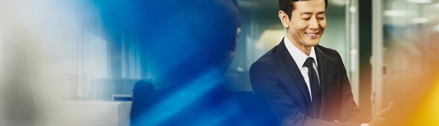 Man and woman talking in an office. Japan. Primary color: blue.